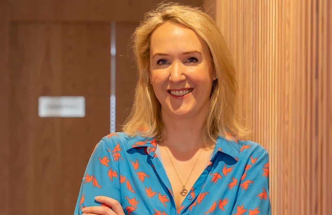 blonde doctor leaning against wall, smiling